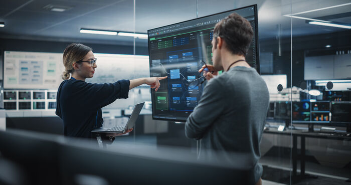 Illustrasjonsfoto av kvinne og mann som studerer data på en skjerm.
