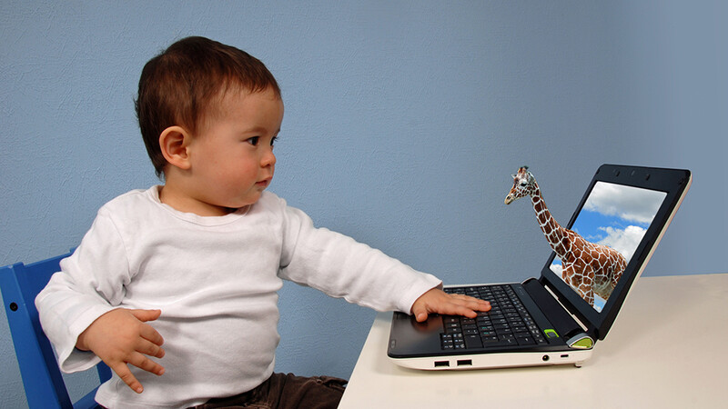 En baby strekker seg mot en dataskjerm. Ut av dataskjermen kommer det en giraff. 