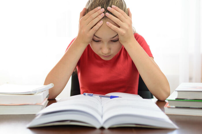 Ung person sitter bekymret med lekser.