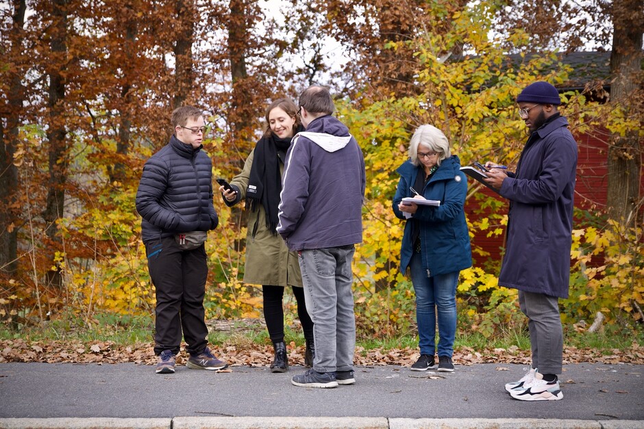 A group of people, looking at a phone and taking notes in notebooks. Autumn scenery.