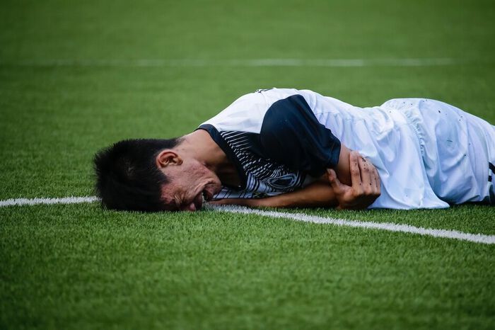 Fotballer lying down on the pitch and crying (closeup)