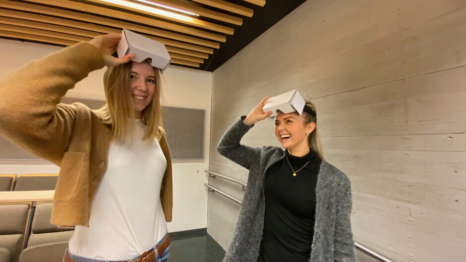 To kvinnelige studenter løfter opp VR-briller fra hodet