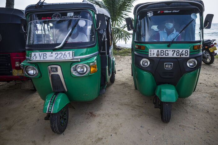 Two rickshaws on a beach road waiting for passengers