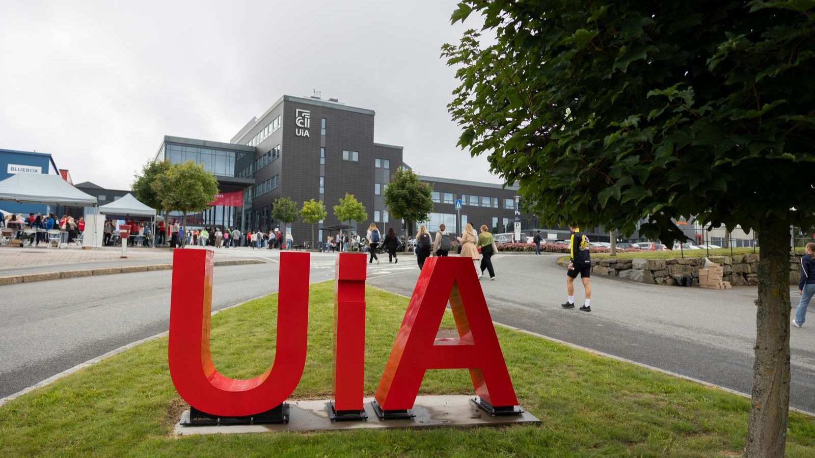 Bilde tatt foran UiA Campus Grimstad. Røde, utskårne UiA-bokstaver i forgrunnen.