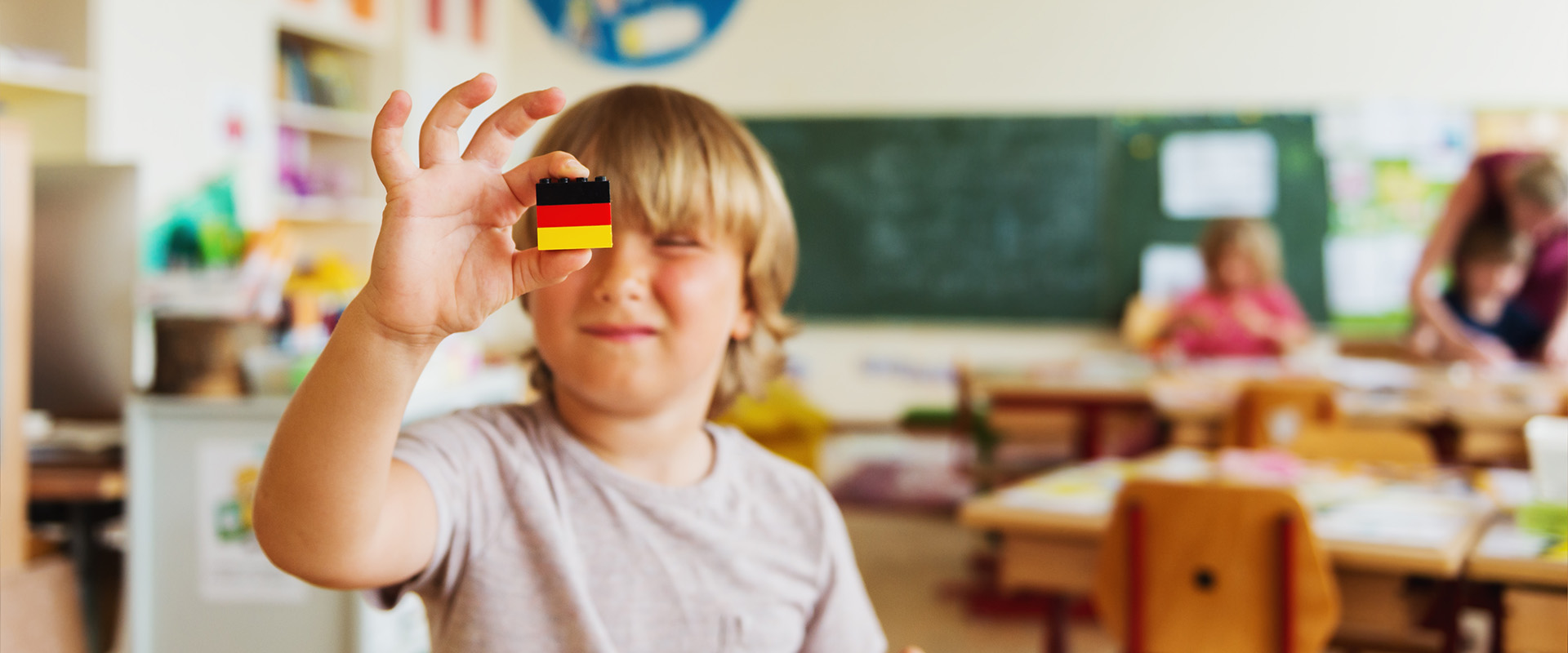 Gutt holder opp tysk flagg laget av legoklosser, klasserom