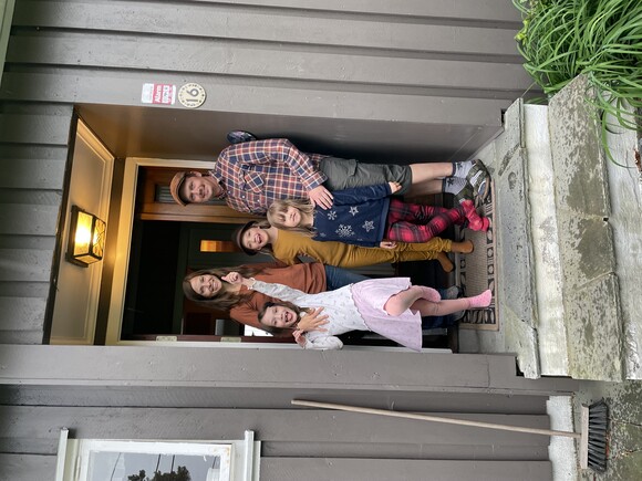 Familien Stensola med to voksne og tre barn står i en døråpning