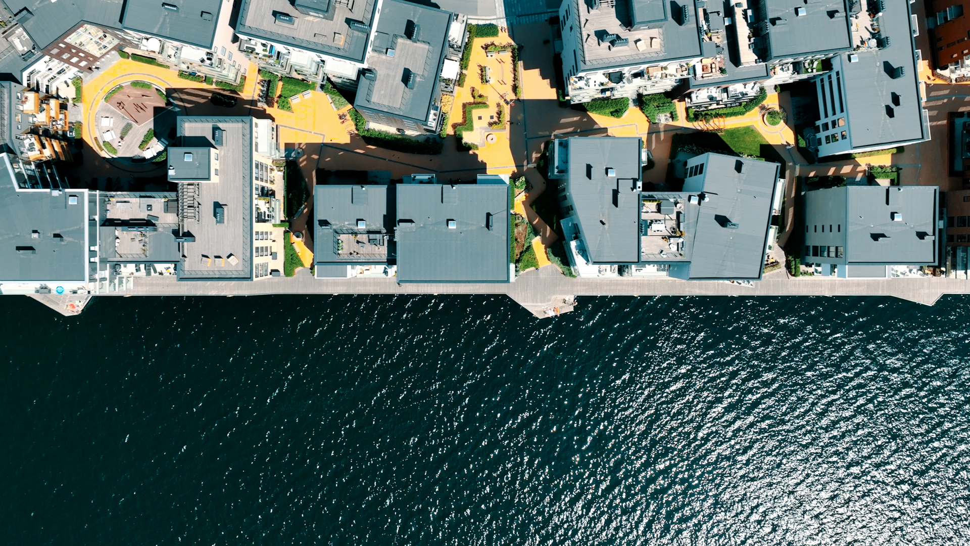 Bilde viser sjø og utbygd boligområde med leiligheter tett på sjøen.