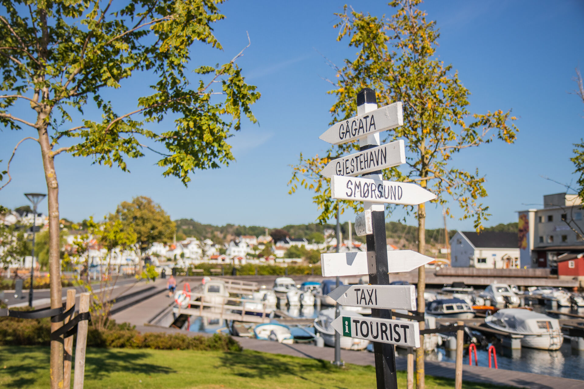 Et veiskilt som peker i mange forskjellige retninger med diverse aktiviteter og Grimstad turistkontor