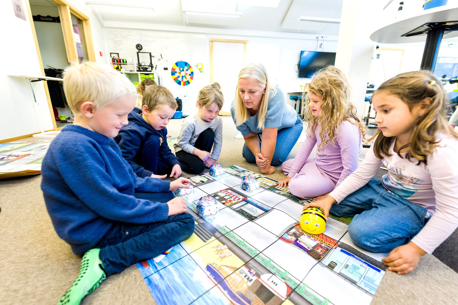 Barnehagelærer sitter med barn på gulvet og leker