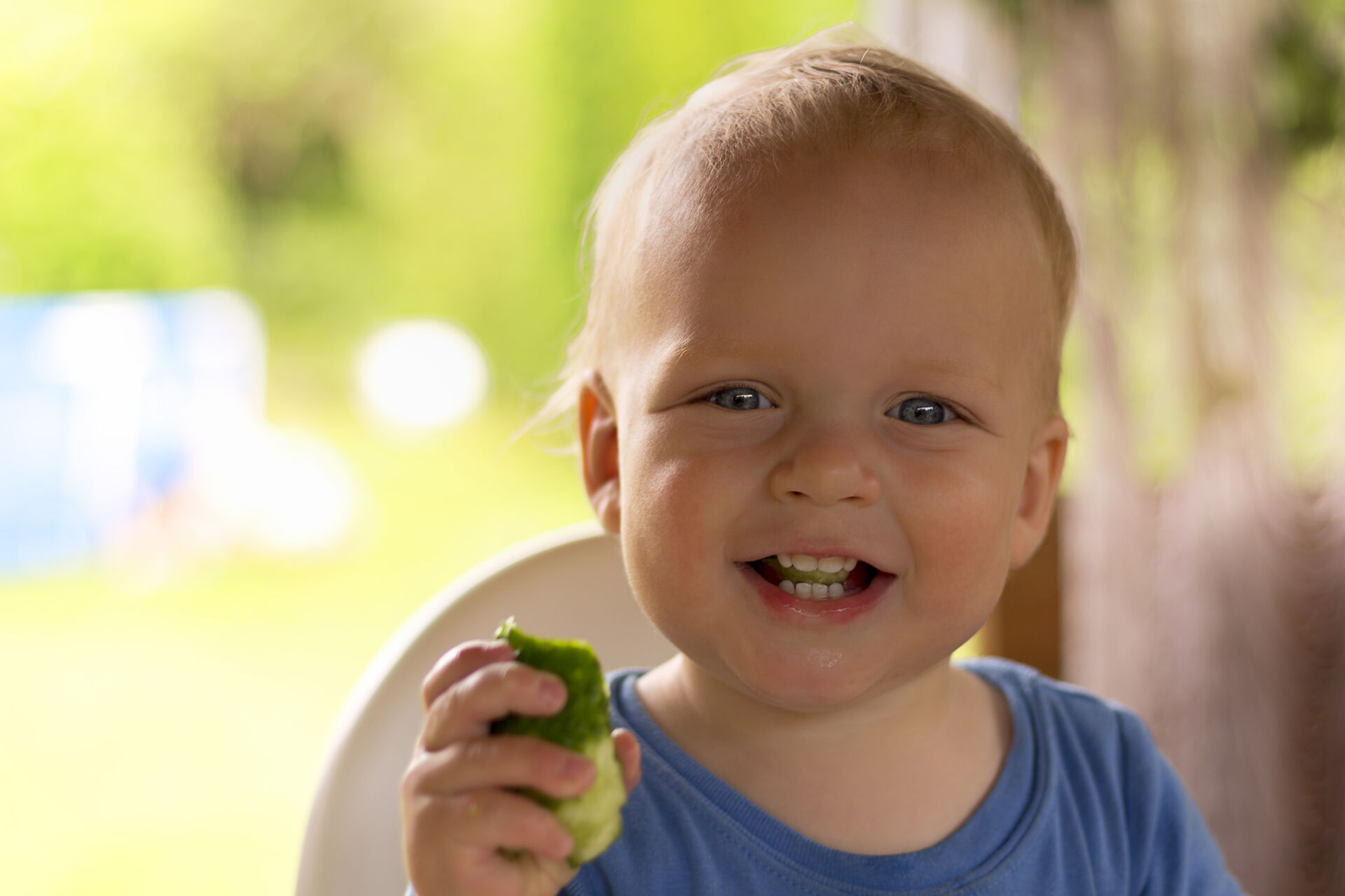 En liten gutt smiler og spiser på et eple