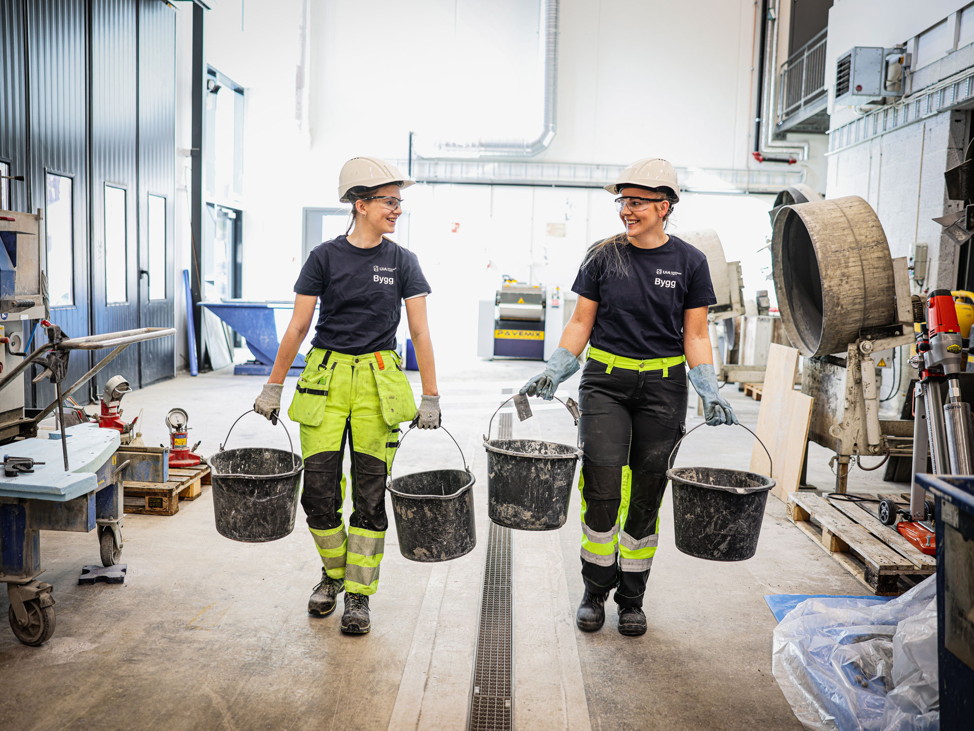 Foto av to byggingeniørstudenter bærer bøtter i lab 