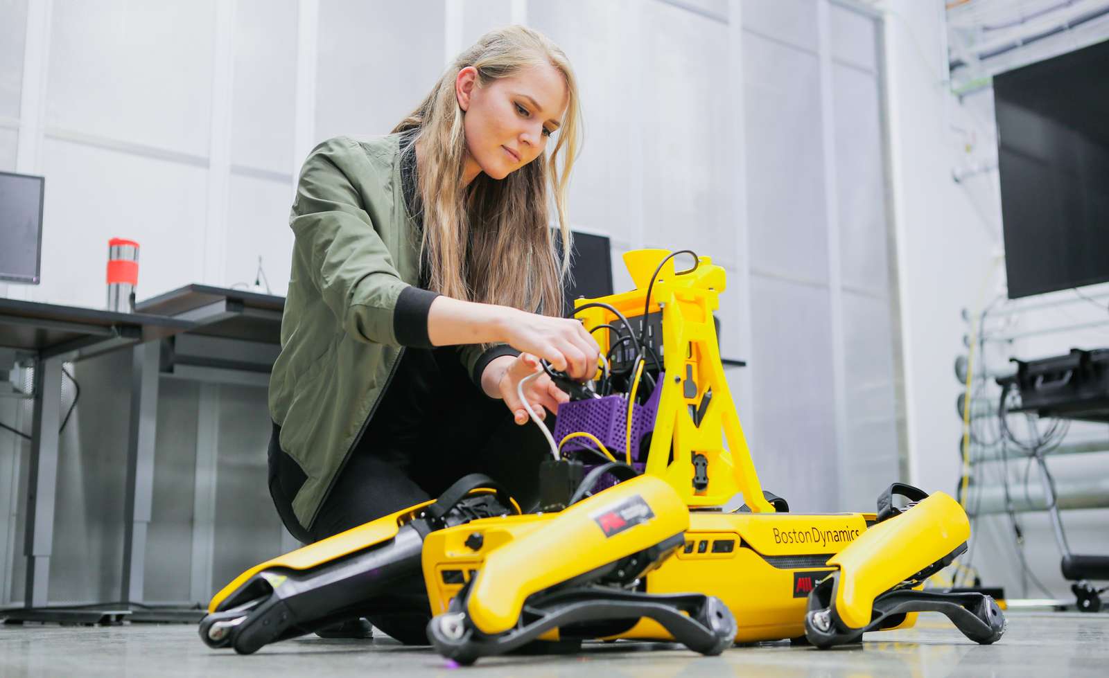 En jente som fikser på en gul robot